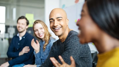 En grupp kollegor sitter och diskuterar glatt under ett möte