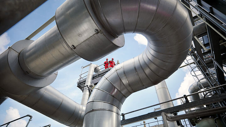 Två manliga servicetekniker utför arbete på ett ventilationssystem på ett tak.