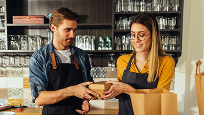 En man och en kvinna packar mat i papperspåsar på en restaurang